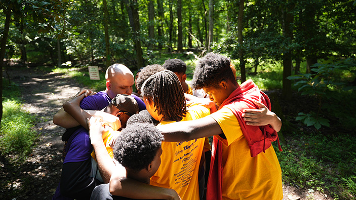 Group of teens in a group hug in an outdoor setting