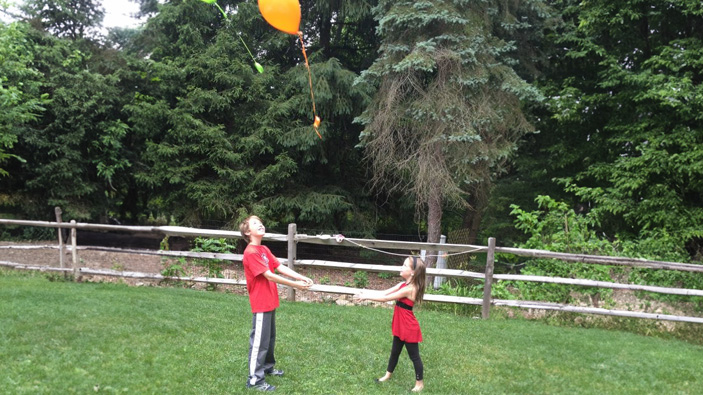 Two siblings letting go of balloons