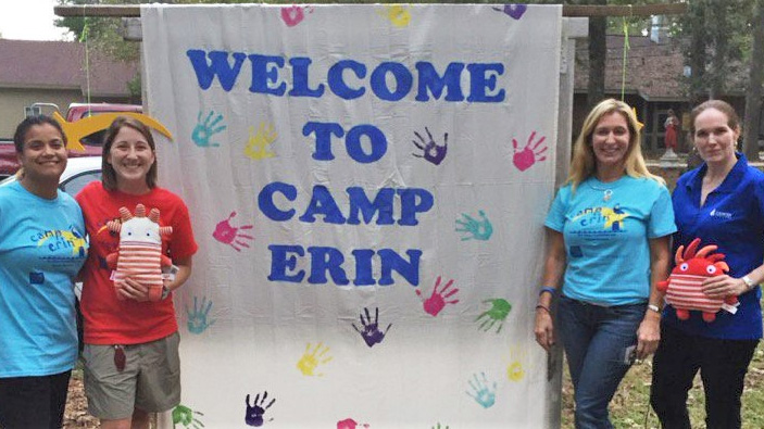 Four women standing by a welcome to camp erin sign