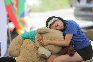 a young girl hugs a giant teddy bear for support