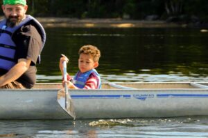 a father and child rowing a canoe at Camp Erin