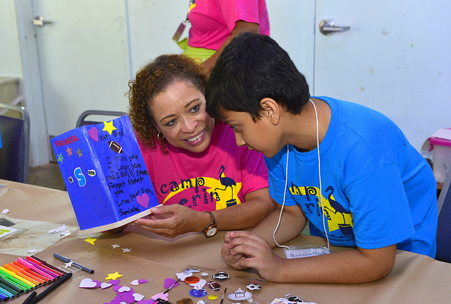 a counselor and camper working on an activity together.