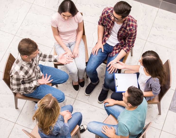 small group of young adults sitting in a circle having a supportive discussion