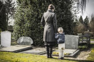 a woman and child stand graveside