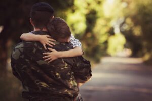 a father dressed in military fatigues hugs his son