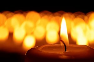 image of a candle for a grief memorial with many candles out of focus in the background