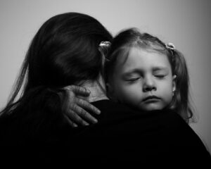 an adult hugs a child in black and white