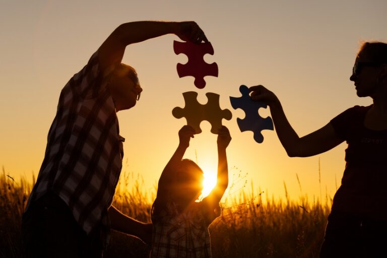 puzzle pieces being fit together by three people