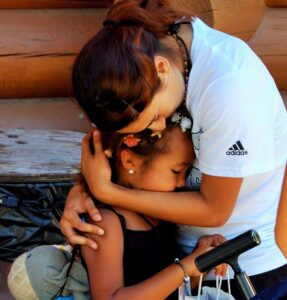 a woman comforts a child as they say good bye at the end of an Eluna camp