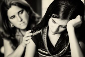 a mother comforts her daughter. image in black and white.