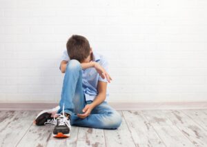 a child grieves while sitting on the floor.